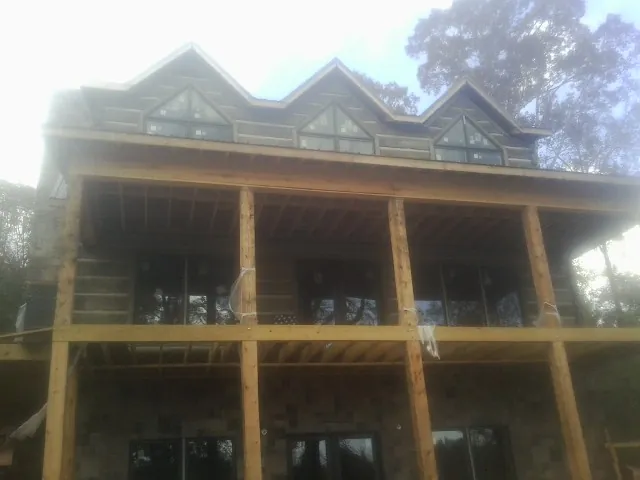 Dormers and porch framing on a large log home under construction — Roof Coating work by our crew in Wapwallopen
