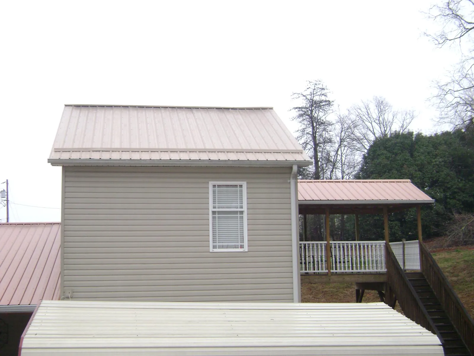 Tan metal roofs on a two story addition and attached porch, from a Roof Replacement job in Wapwallopen