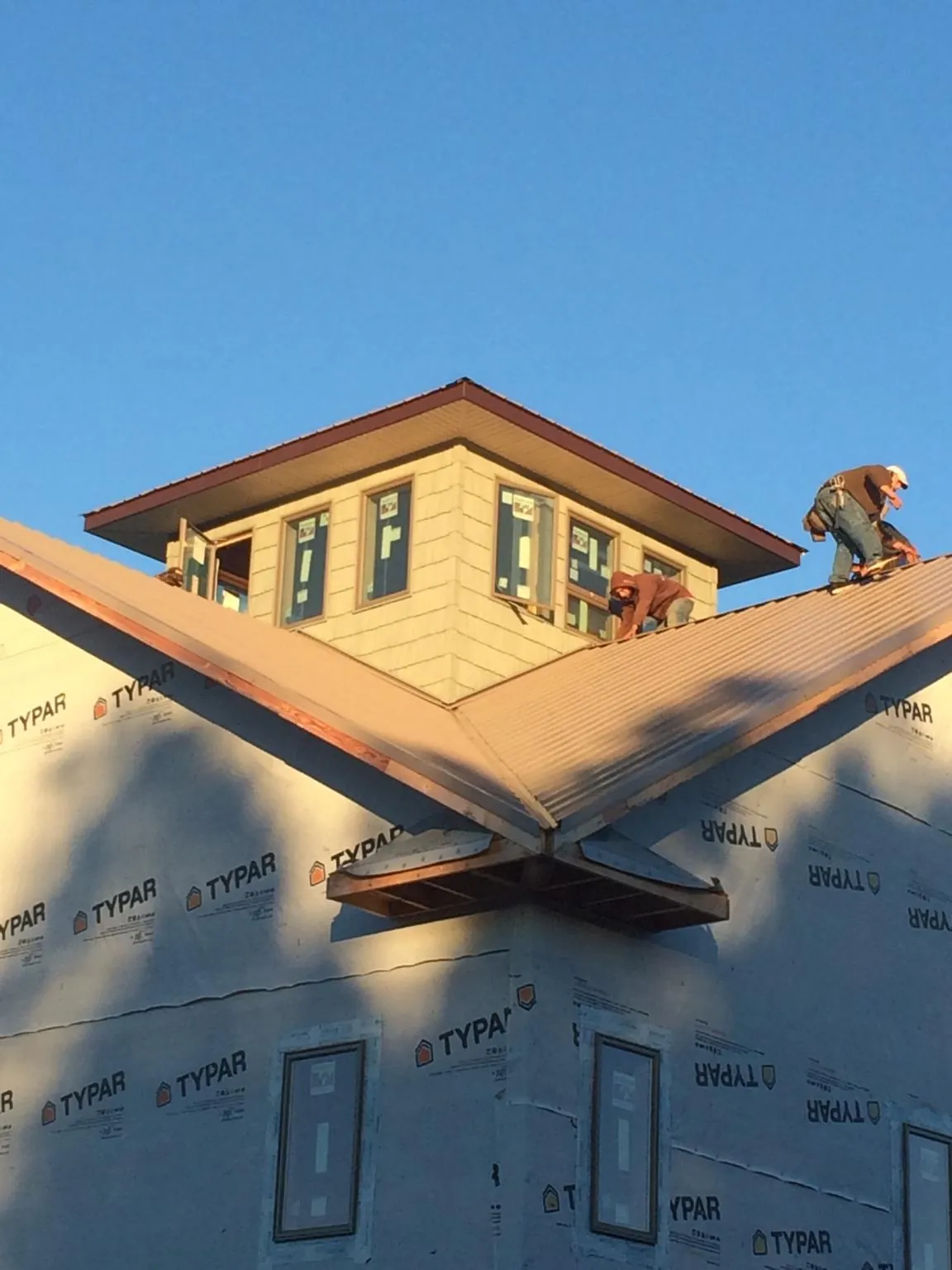 Roofers working around a rooftop cupola on a new metal roof at sunset — Roof Waterproofing in Wapwallopen by Roofing Brothers